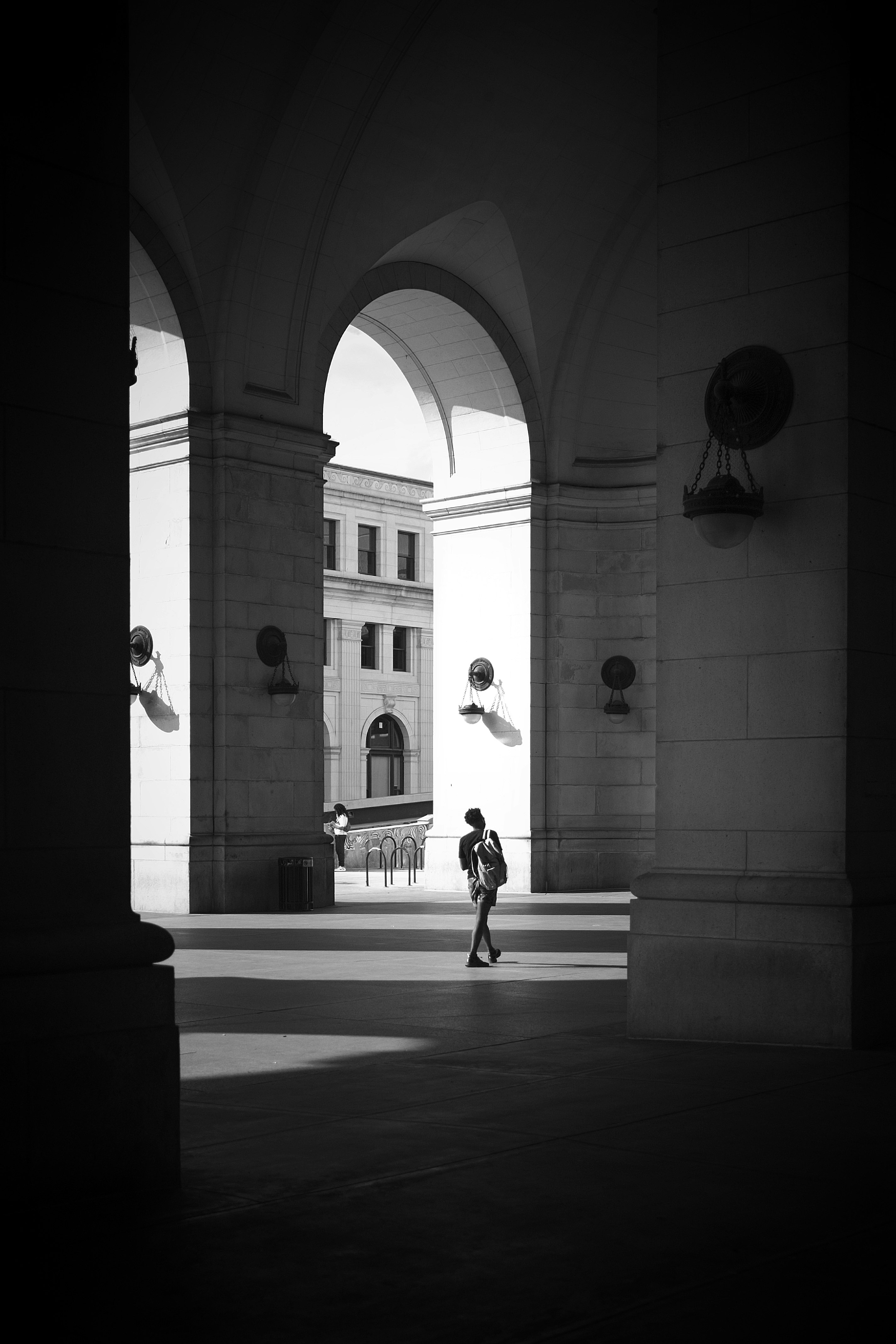 man in black jacket and pants walking on sidewalk during daytime